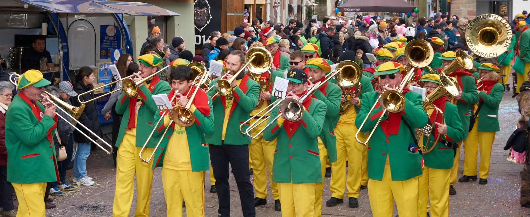 Brass band in green and yellow carnival costumes on street