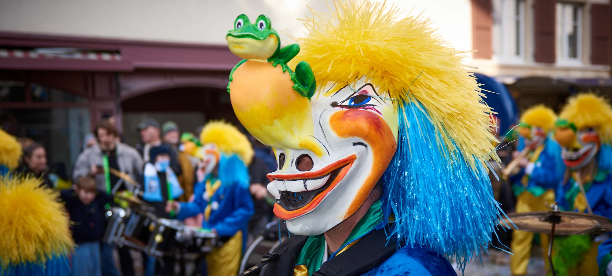 Clown mit gelbem Haar und grünem Frosch beim Fasnachtsumzug
